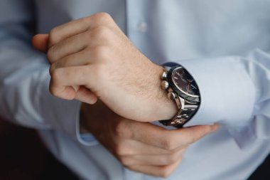 Close-up hands of the groom in a blue shirt with a watches