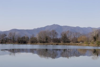 Ağaçlar ve dağlar gölde yansıyan.
