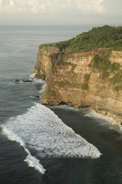 Las olas del océano rompiendo en las rocas al pie de un acantilado de montaña — Foto de Stock