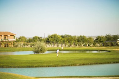 Bir adam üzerinde yeşil bir alana golf oynuyor.