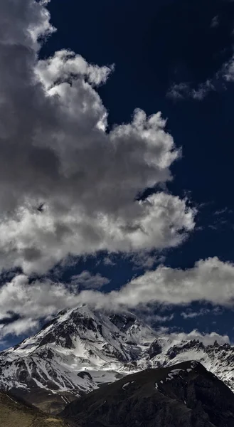 Nubes en el cielo azul golpearon la cima del magnífico Kazbek. Mo. —  Fotos de Stock