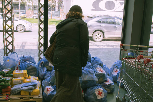 Tbilisi Republic of Georgia, 2020 year, March  month, 31. An elderly local woman considers donations from a supermarket, packaged grocery sets for charity purposes.