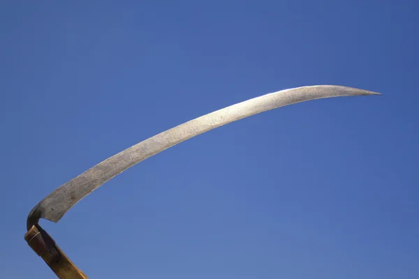 Metal scythe against blue sky — Stock Photo, Image