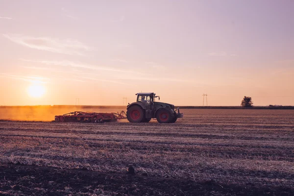 Traktor plöjer under solnedgången — Stockfoto