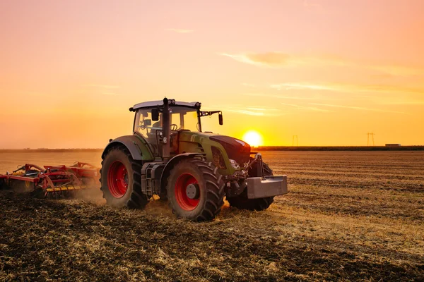 Pembajakan traktor selama matahari terbenam Stok Foto