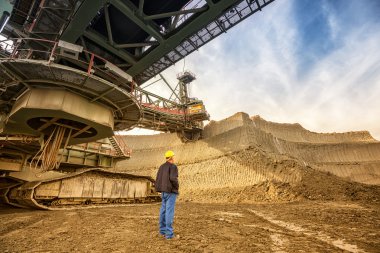 man standing near bucket wheel excavator clipart