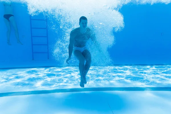 水中の楽しい 若いハンサムな男は水中水泳 スイミングの世論調査でダイビングします スポーツとレジャー — ストック写真