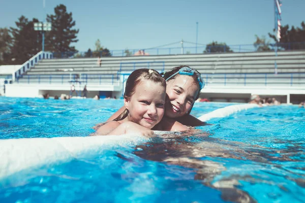 Underwater fun. Two cute little girls with goggles swimming underwater and diving in the swimming poll. Kids sport and leisure