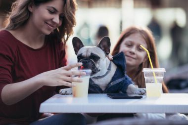 Anne ve kızı ile onların Fransız buldozer kafeteryasında zevk. Seçici odak üstünde köpek