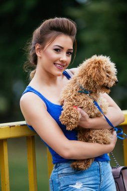 Küçük kırmızı fino köpeği ile köprü üzerinde duran güzel gülümseyen genç kadın portresi