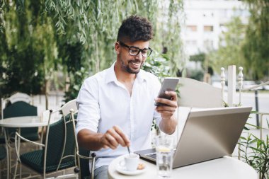 Olumlu ve çekici Afro Amerikalı işadamı cafe bar üstünde laptop bazı işler yapıyor ve kahve içme otururken