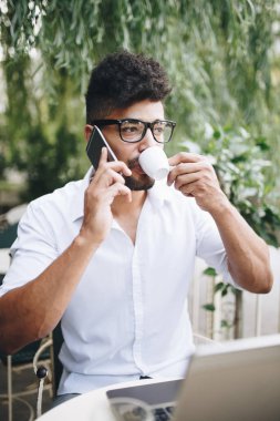 Olumlu ve çekici Afro Amerikalı işadamı cafe bar üstünde laptop bazı işler yapıyor ve kahve içme otururken