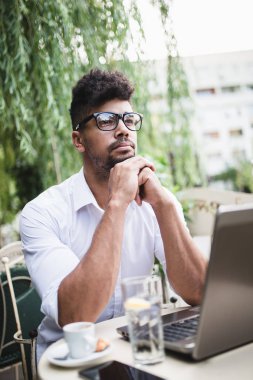 Olumlu ve çekici Afro Amerikalı işadamı cafe bar üstünde laptop bazı işler yapıyor ve kahve içme otururken