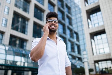 Büyük modern iş kurma gülümseyen ve cep telefonuyla konuşurken önünde duran genç Afro Amerikan yakışıklı