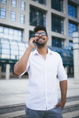 Büyük modern iş kurma gülümseyen ve cep telefonuyla konuşurken önünde duran genç Afro Amerikan yakışıklı