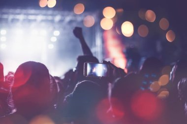 Siluetleri festival konser kalabalığın önünde parlak sahne ışıkları. Tanınmayan insanlar ve renkli etkileri