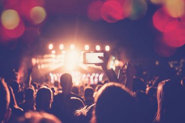 Siluetleri festival konser kalabalığın önünde parlak sahne ışıkları. Tanınmayan insanlar ve renkli etkileri
