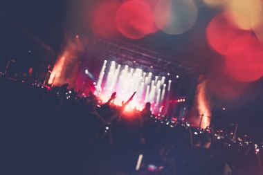 Siluetleri festival konser kalabalığın önünde parlak sahne ışıkları. Tanınmayan insanlar ve renkli etkileri