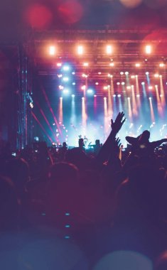 Siluetleri festival konser kalabalığın önünde parlak sahne ışıkları. Tanınmayan insanlar ve renkli etkileri