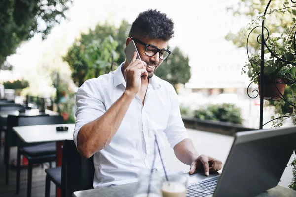 Olumlu ve çekici Afro Amerikalı işadamı cafe bar üstünde laptop bazı işler yapıyor ve kahve içme otururken