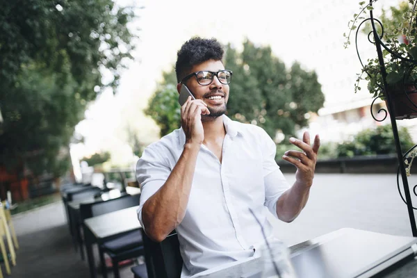 Olumlu ve çekici Afro Amerikalı işadamı cafe bar üstünde laptop bazı işler yapıyor ve kahve içme otururken