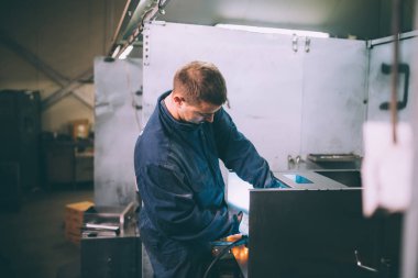 Metalurji Sanayi. Fabrika üretim ağır Pelet soba ve kazanlar için. Onun iş işçi ressam. Son derece karanlık koşulları ve görünür gürültü