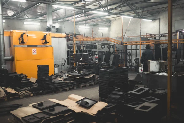 Metallurgy industry. Factory for production of heavy pellet stoves and boilers. Manual worker painter on his job. Extremely dark conditions and visible noise