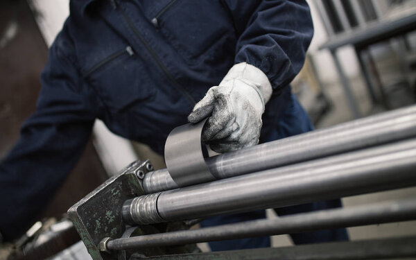 Metallurgy industry. Factory for production of heavy pellet stoves and boilers. Close up of manual worker welder on his job. Extremely dark conditions and visible noise