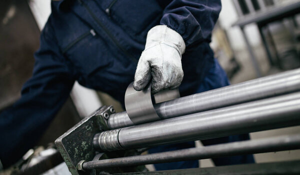 Metallurgy industry. Factory for production of heavy pellet stoves and boilers. Close up of manual worker welder on his job. Extremely dark conditions and visible noise