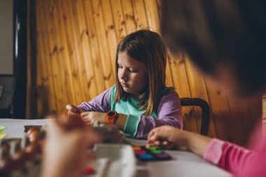 Paskalya tatil keyfini iki kız. Onlar boyama ve yumurta dekorasyon mutfak masasına oturuyorlar