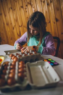 Paskalya tatil keyfi küçük kız. Boyama ve yumurta dekorasyon mutfak masasında oturuyor