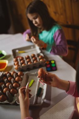 Paskalya tatil keyfini iki kız. Onlar boyama ve yumurta dekorasyon mutfak masasına oturuyorlar