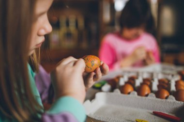 Paskalya tatil keyfini iki kız. Onlar boyama ve yumurta dekorasyon mutfak masasına oturuyorlar