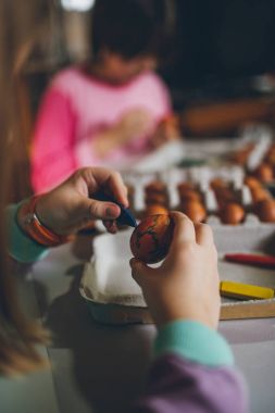 Paskalya tatil keyfini iki kız. Onlar boyama ve yumurta dekorasyon mutfak masasına oturuyorlar