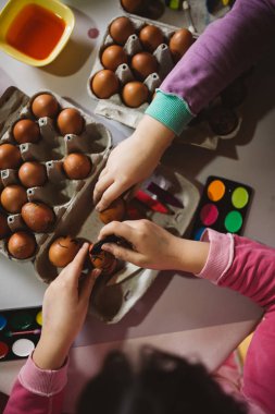 Paskalya tatil keyfini iki kız. Onlar boyama ve yumurta dekorasyon mutfak masasına oturuyorlar