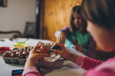 Paskalya tatil keyfini iki kız. Onlar boyama ve yumurta dekorasyon mutfak masasına oturuyorlar