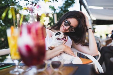 Sevimli Fransız bulldog köpeği ile kafede oturan güzel genç kadın. Köpekler Tema grubu