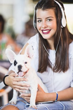 Sevimli Fransız bulldog köpeği ile kafede oturan güzel genç kadın. Açık havada bahar ya da yaz şehir. Köpekler Tema grubu