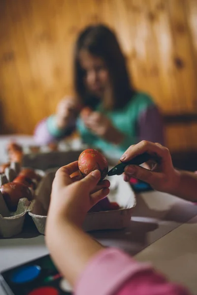 stock image Two girls enjoying in Easter holiday. They are sitting at kitchen table, painting and decorating eggs