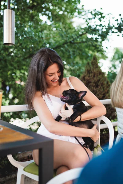 Beautiful young woman sitting in cafe with her adorable French bulldog puppy. People with dogs theme