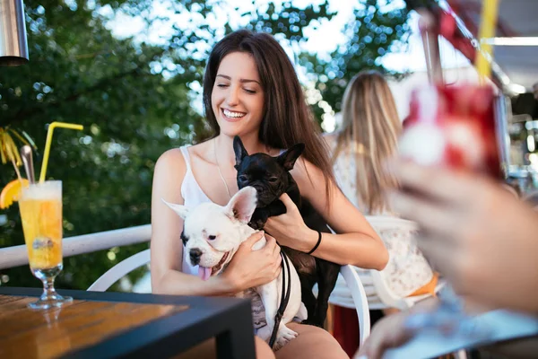 Beautiful young woman sitting in cafe with her adorable French bulldog puppy. People with dogs theme