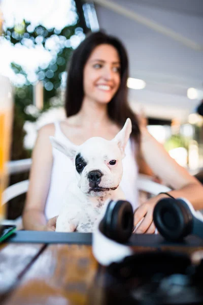 Beautiful young woman sitting in cafe with her adorable French bulldog puppy. People with dogs theme