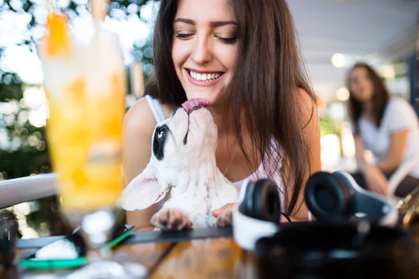 Beautiful young woman sitting in cafe with her adorable French bulldog puppy. People with dogs theme