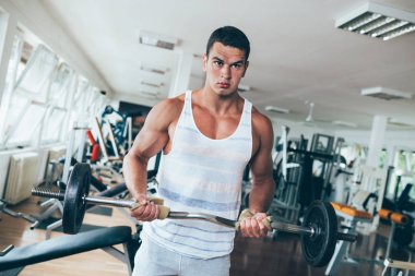 Egzersiz ve fitness spor salonunda ağırlık kaldırma işi genç çekici yetişkin bir adam. Kapalı eğitim spor