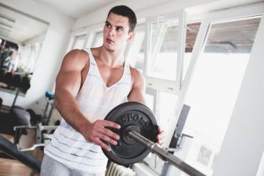 Egzersiz ve fitness spor salonunda ağırlık kaldırma işi genç çekici yetişkin bir adam. Kapalı eğitim spor