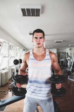 Egzersiz ve fitness spor salonunda ağırlık kaldırma işi genç çekici yetişkin bir adam. Kapalı eğitim spor
