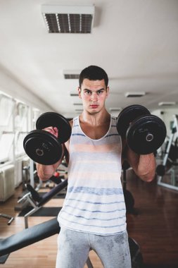 Egzersiz ve fitness spor salonunda ağırlık kaldırma işi genç çekici yetişkin bir adam. Kapalı eğitim spor