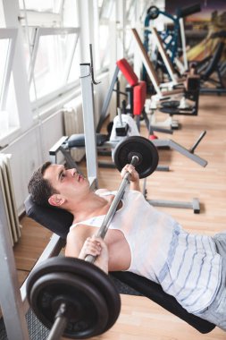 Egzersiz ve fitness spor salonunda ağırlık kaldırma işi genç çekici yetişkin bir adam. Kapalı eğitim spor