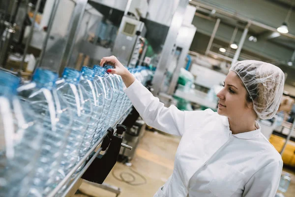 女工检查机器人生产线瓶装和包装纯净的饮用水瓶和罐 — 图库照片