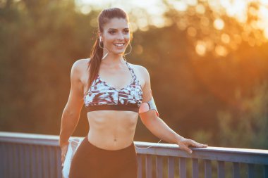 Çalışan ve açık havada Şehir Köprüsü'nde germe güzel atletik bir kadın. Günbatımı renkleri